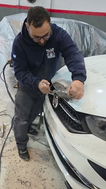 Técnico trabajando en la trompa de un auto blanco